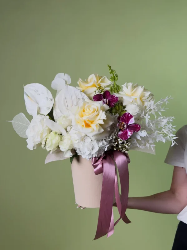 Aranjament elegant cu trandafiri crem, anthurium alb cu perle, hortensie albă și orhidee mov-magenta